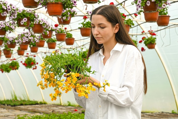 Vrouwelijke boer die voor plant zorgt die bloemen in kas onderzoekt mensen baan en levensstijl concept