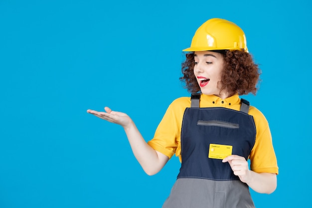 Vrouwelijke bouwer in uniform met creditcard op een blauw