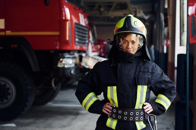 Vrouwelijke brandweerman in beschermend uniform staande in de buurt van vrachtwagen