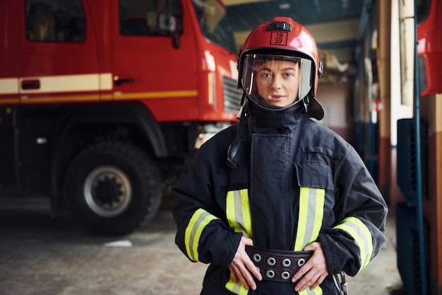 Vrouwelijke brandweerman in beschermend uniform staande in de buurt van vrachtwagen