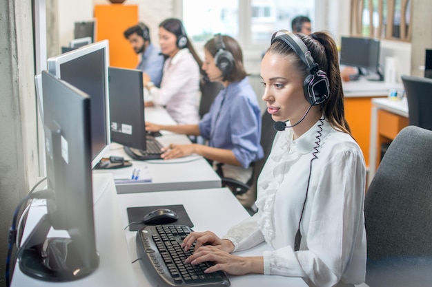 Vrouwelijke callcenteragent die klant online adviseert terwijl ze in een callcenter werkt