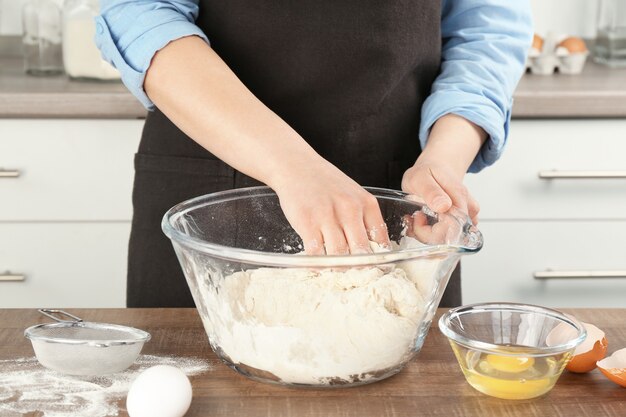 Vrouwelijke chef-kok die deeg in keuken maakt