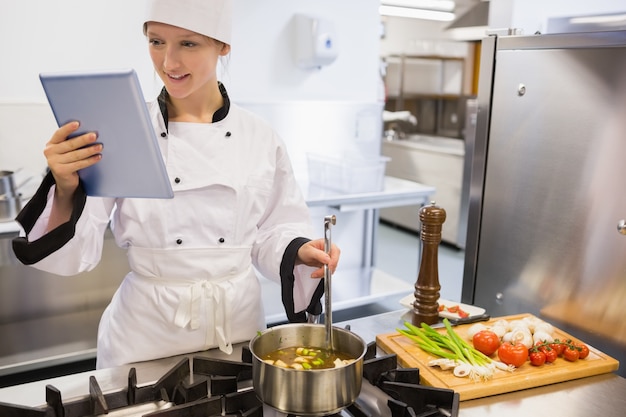 Vrouwelijke chef-kok die tabletpc met behulp van terwijl het koken