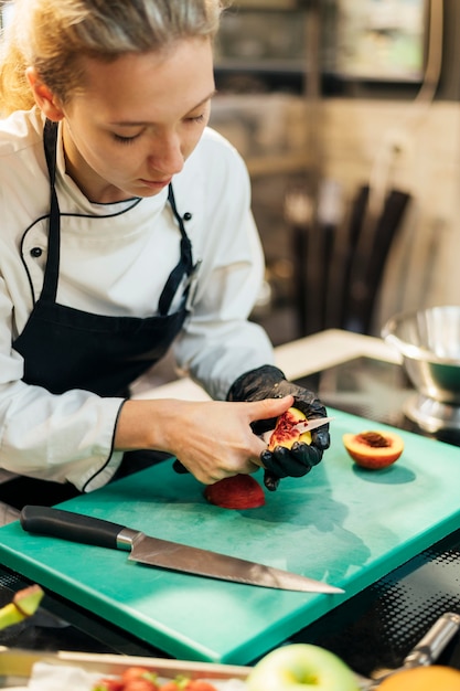 Foto vrouwelijke chef-kok fruit snijden in de keuken