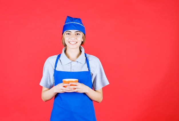 Vrouwelijke chef-kok in blauwe schort met een noedelbeker