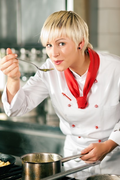 Vrouwelijke Chef-kok in restaurantkeuken het proeven