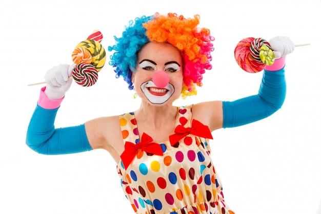 Vrouwelijke clown in de kleurrijke lollys van de pruikenholding in beide handen