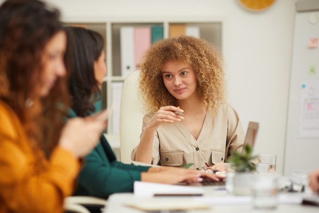 Vrouwelijke collega's chatten tijdens vergadering