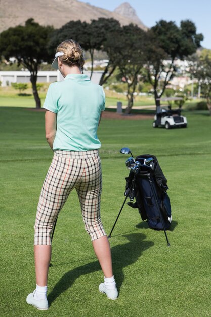 Vrouwelijke concentrerende golfspeler afslag op een zonnige dag op de golfbaan