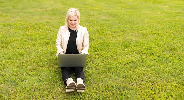 Vrouwelijke copywriter bezig met laptop in het park, uitzicht over de schouder.