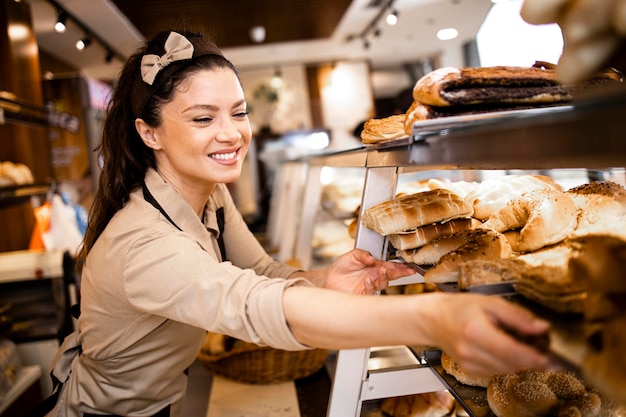 vrouwelijke deli-werknemer in uniform verkopen van vers gefokt in de bakkerij-afdeling van de supermarkt
