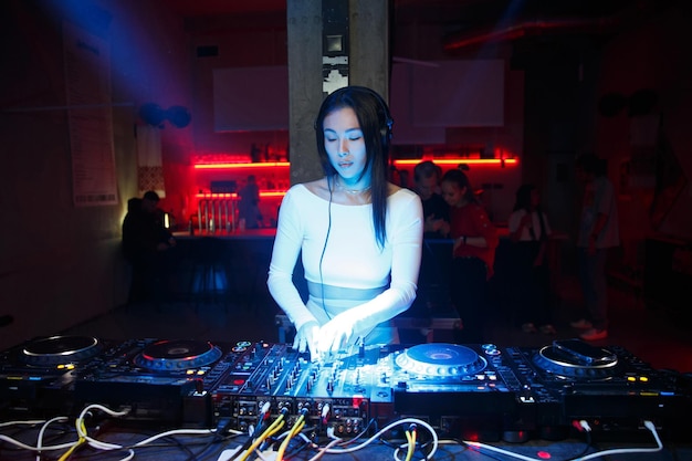 Foto vrouwelijke dj speelt muziek in een nachtclub of ander evenement met behulp van dj-apparatuur