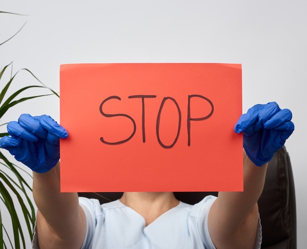 Foto vrouwelijke dokter met een vel papier met het opschrift stop