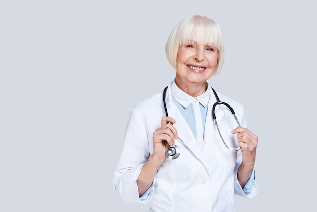 Vrouwelijke dokter. mooie senior vrouw in laboratoriumjas camera kijken en glimlachen