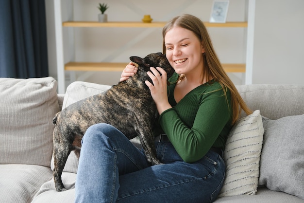 Vrouwelijke eigenaar speelt met vrolijke hond thuis Spelen met hondenconcept