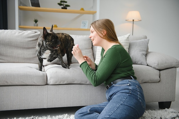 Vrouwelijke eigenaar speelt met vrolijke hond thuis Spelen met hondenconcept