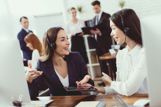 Vrouwelijke exploitanten van een callcenter communiceren met elkaar.