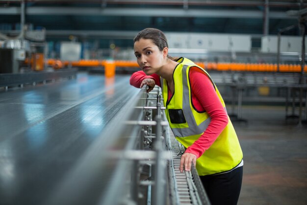 Vrouwelijke fabrieksarbeider die transportband controleert