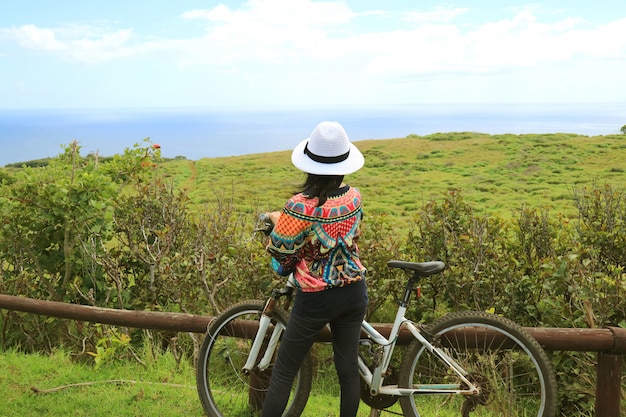 Vrouwelijke fietser die de toneel Vreedzame oceaan van Rano Kau-vulkaan op Pasen-Eiland, Chili bewonderen