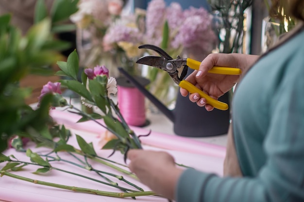 Vrouwelijke florist39s handen close-up combineert roze rozen met groene takken om een prachtig boeket te creëren