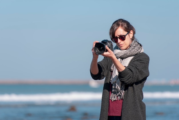 vrouwelijke fotograaf die een foto maakt op het strand