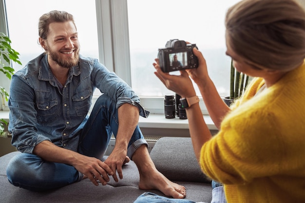 Vrouwelijke fotograaf die foto's maakt van haar vriendje thuis