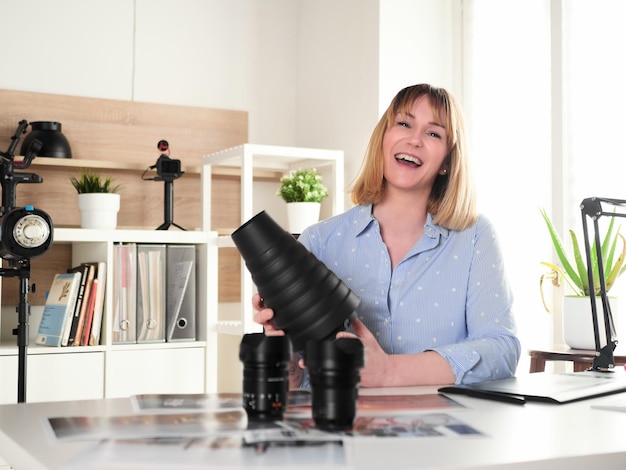 Foto vrouwelijke fotograaf die in de kantoorstudio werkt en een snootreflector vasthoudt