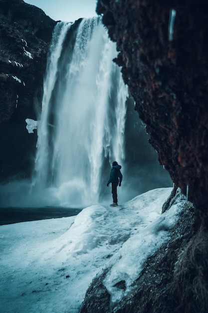 Vrouwelijke fotograaf in de winter in IJsland die de Skogafoss-waterval bezoekt