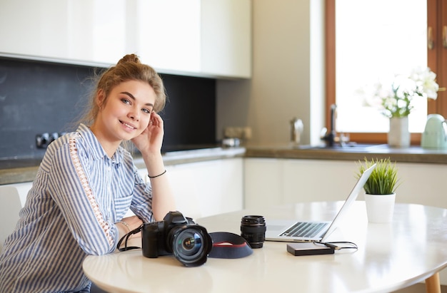 Vrouwelijke fotograaf zittend op het bureau met laptop