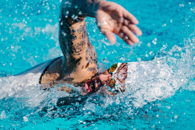 Vrouwelijke front crawl zwemmer met tatoeages tijdens de training