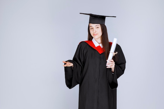 Vrouwelijke gediplomeerde student in toga met universiteitscertificaat status. hoge kwaliteit foto