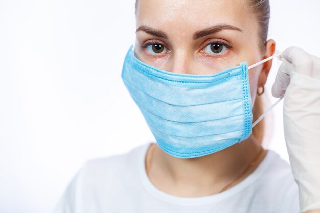 Vrouwelijke gezondheidswerker laat zien hoe je een beschermend medisch chirurgisch masker tegen het virus draagt. Geïsoleerd op witte achtergrond