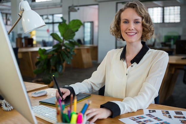 Vrouwelijke grafisch ontwerper die bij bureau werkt