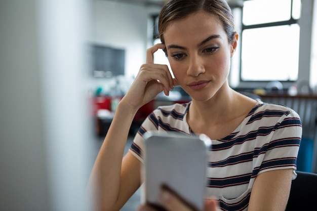 Vrouwelijke grafisch ontwerper met behulp van mobiele telefoon