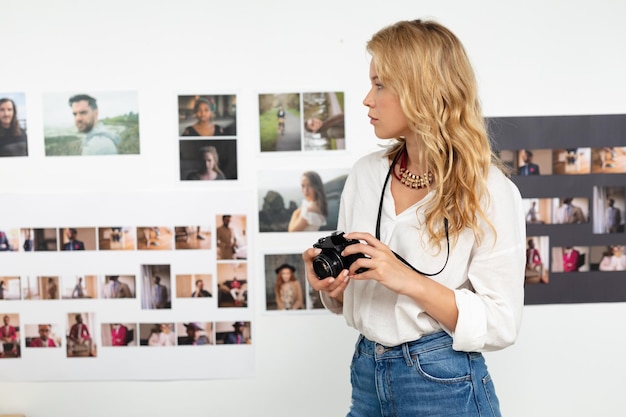 Foto vrouwelijke grafische ontwerper die foto's op een digitale camera in het kantoor beoordeelt