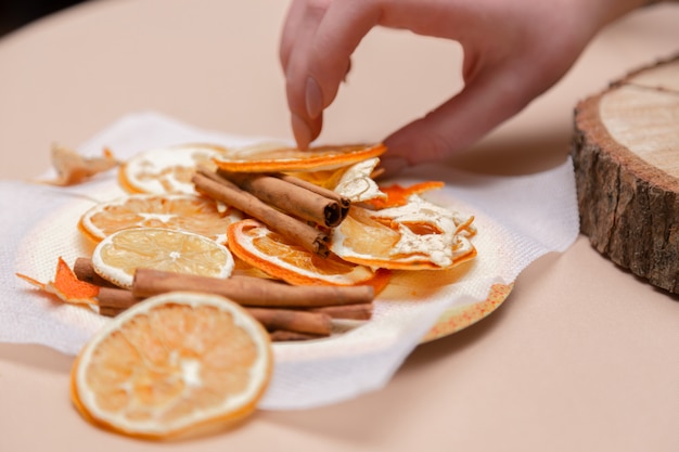 vrouwelijke hand decoraties maken van gedroogde sinaasappels, sterren van mandarijn en kaneel