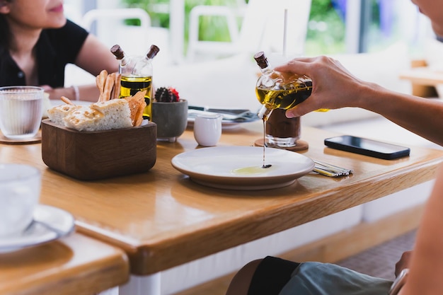 Vrouwelijke hand die balsamico-azijnsaus op een witte bord bij de eettafel giet