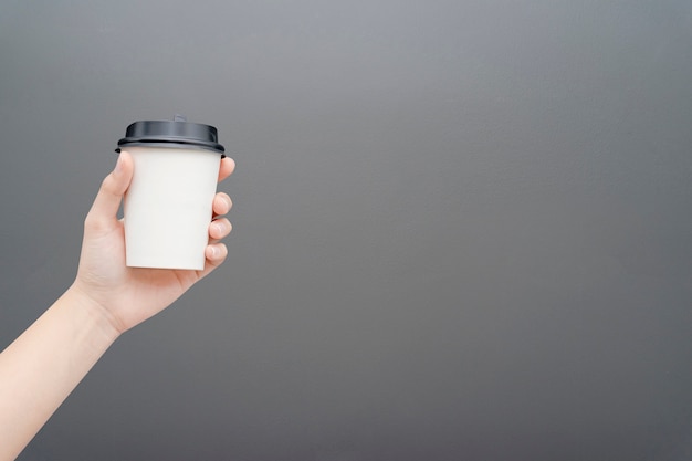 Vrouwelijke hand die een koffiedocument kop op grijs houdt