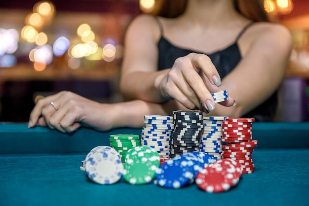 Vrouwelijke hand die pokerfiches van stapel neemt