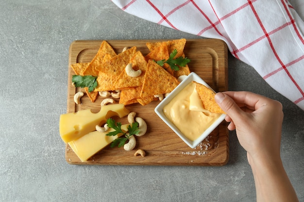 Vrouwelijke hand dips chip in kaassaus op snacks achtergrond, bovenaanzicht