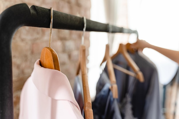 Vrouwelijke hand en houten hangers met verschillende outfits in de kast