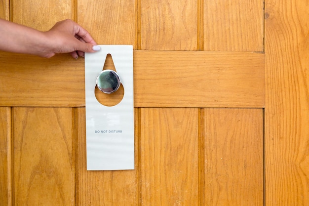 Vrouwelijke hand hangt een bordje aan de deur niet storen in hotel