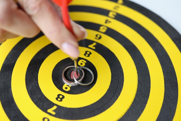 Vrouwelijke hand houdt dart en ringen in het midden van het dartbord