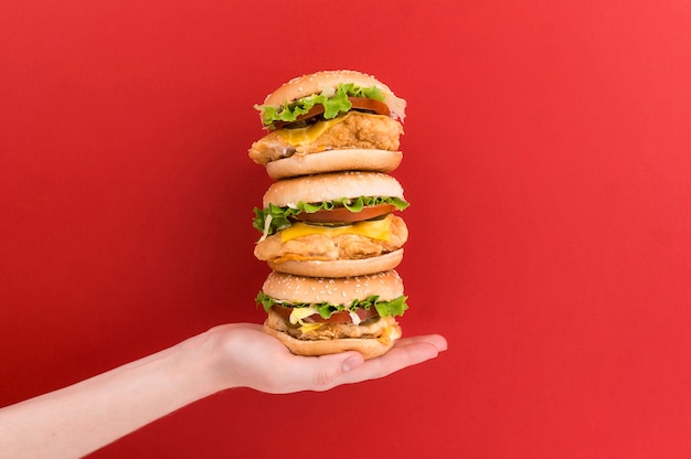 Vrouwelijke hand houdt een piramide van drie hamburgers