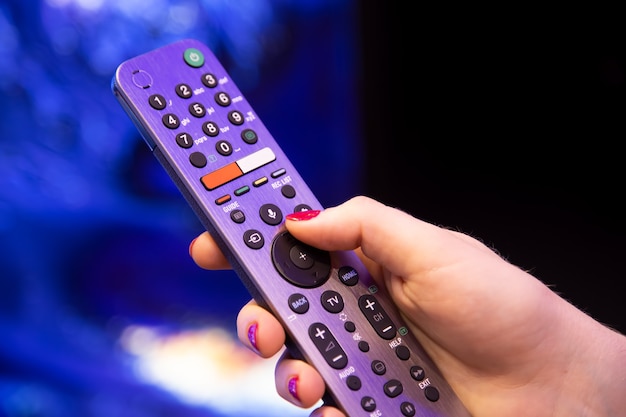 Vrouwelijke hand houdt een slimme tv-afstandsbediening met microfoon en spraakbesturing vast