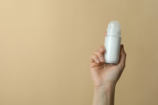 Vrouwelijke hand houdt lege deodorant op beige achtergrond