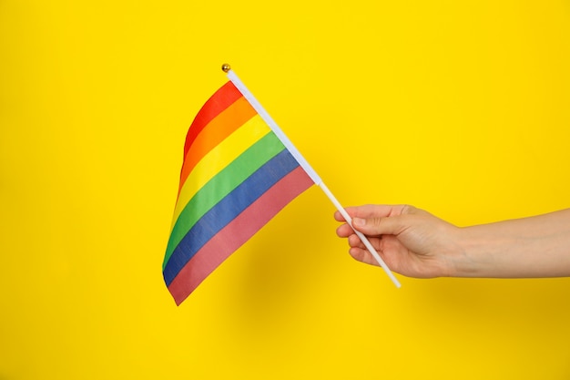 Vrouwelijke hand houdt LGBT-vlag op geel