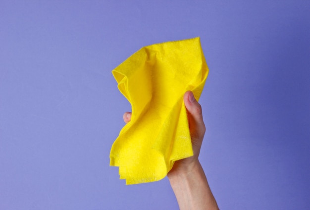 Vrouwelijke hand houdt schoonmaakdoekje voor op paars