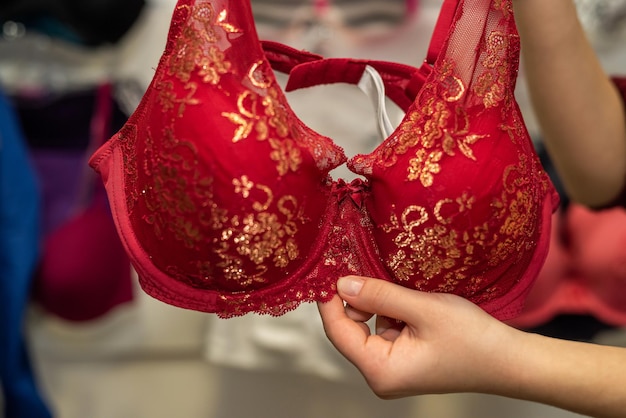Vrouwelijke hand kiest sexy rode beha in lingeriewinkel. vrouwen ondergoed