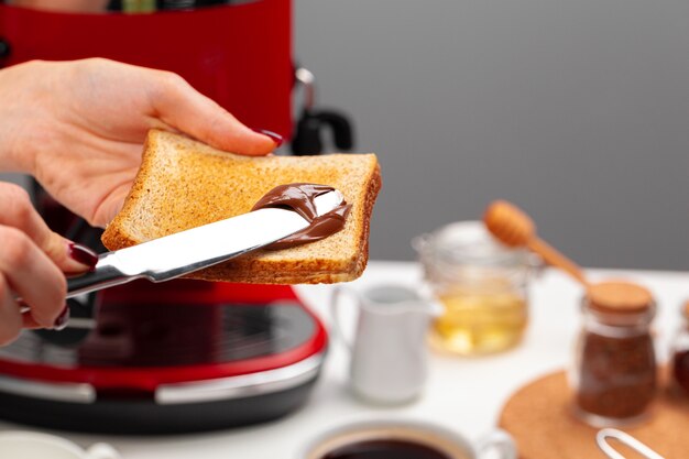 Vrouwelijke hand koken toast met chocolade pasta